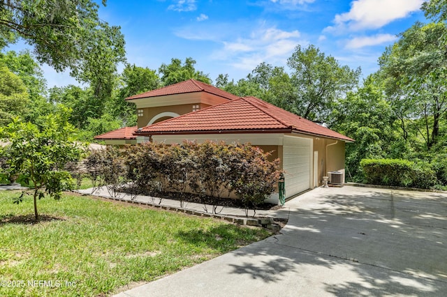 view of side of property featuring central AC, a garage, and a lawn