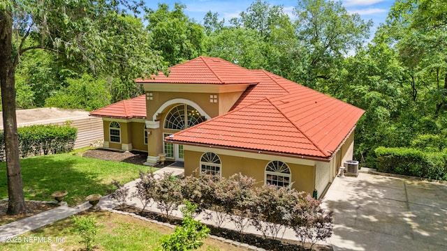 mediterranean / spanish-style home with a garage, central AC, and a front lawn