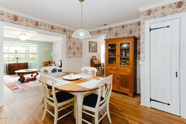 dining area with light hardwood / wood-style flooring and ornamental molding