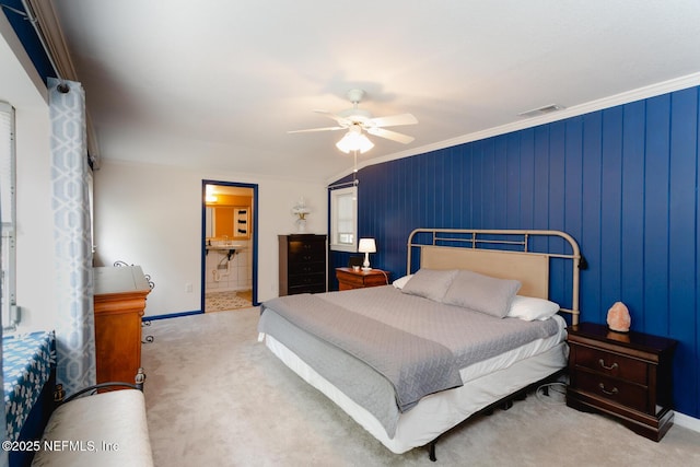 carpeted bedroom with ensuite bath, ceiling fan, and ornamental molding