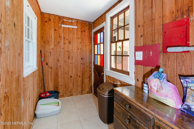 doorway to outside featuring light tile patterned flooring and wooden walls