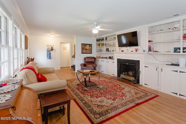 living room with ceiling fan, crown molding, and light hardwood / wood-style floors