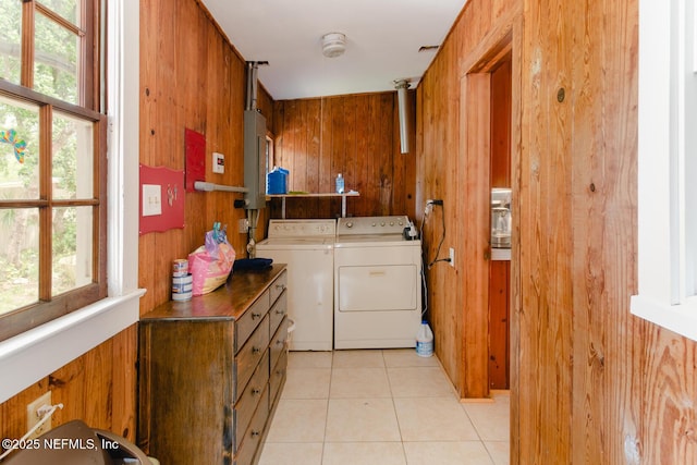 laundry room featuring light tile patterned floors, wood walls, and washing machine and clothes dryer