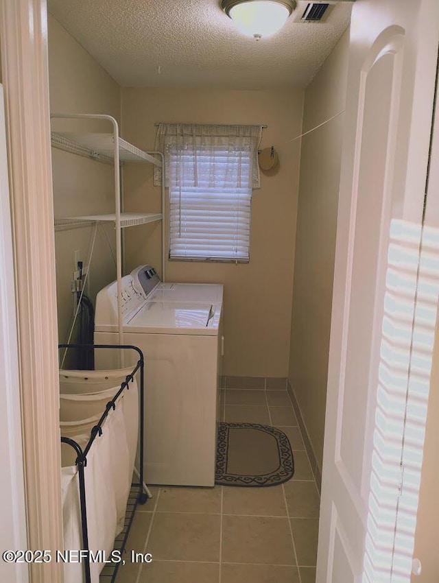 laundry room with light tile patterned floors, washing machine and dryer, sink, and a textured ceiling