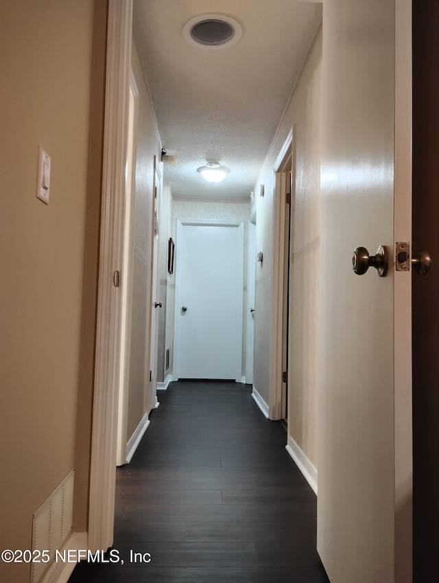 corridor featuring ornamental molding, dark hardwood / wood-style floors, and a textured ceiling