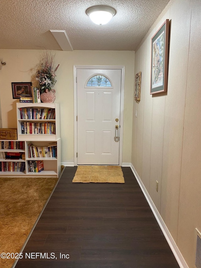 doorway featuring dark hardwood / wood-style flooring and a textured ceiling