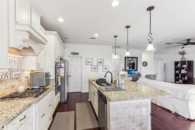 kitchen featuring light stone counters, an island with sink, pendant lighting, stainless steel appliances, and white cabinets