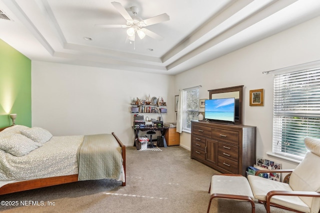 bedroom featuring a raised ceiling, light colored carpet, and ceiling fan