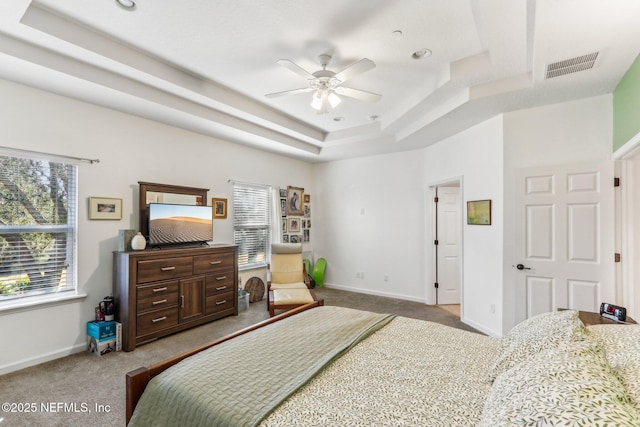 bedroom with ceiling fan, carpet flooring, a tray ceiling, and multiple windows