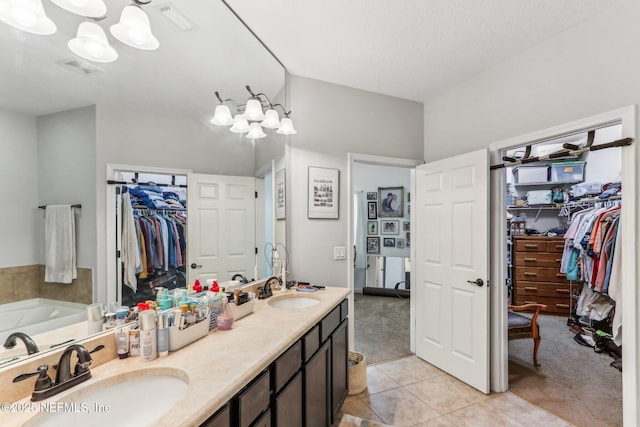 bathroom featuring vanity, tile patterned flooring, a tub, and an inviting chandelier