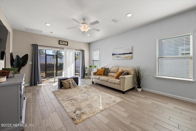 living room with ceiling fan, light hardwood / wood-style floors, and a textured ceiling