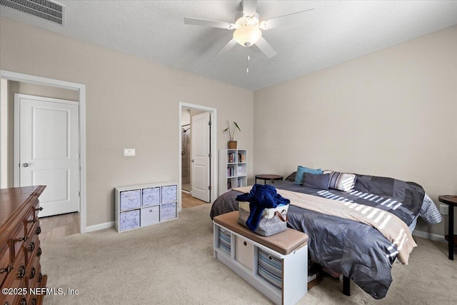 bedroom with ceiling fan, a textured ceiling, and light carpet