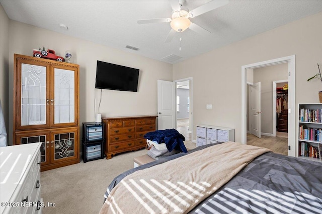 carpeted bedroom featuring a closet, ceiling fan, a spacious closet, and a textured ceiling