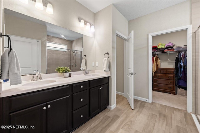 bathroom with vanity, a shower with shower door, a textured ceiling, and hardwood / wood-style flooring