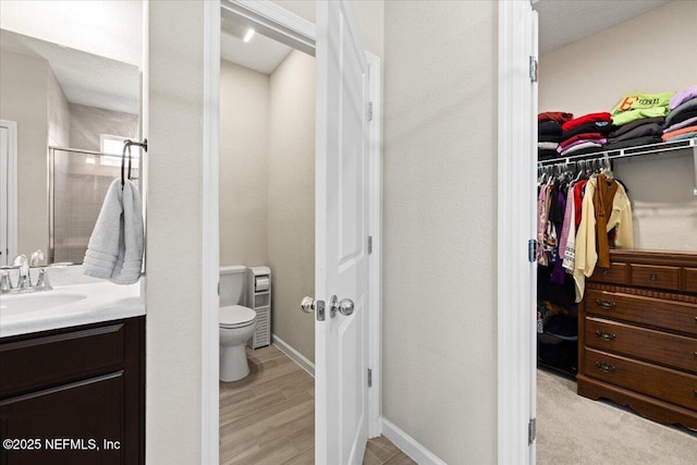 bathroom featuring a shower with shower door, hardwood / wood-style floors, toilet, and vanity