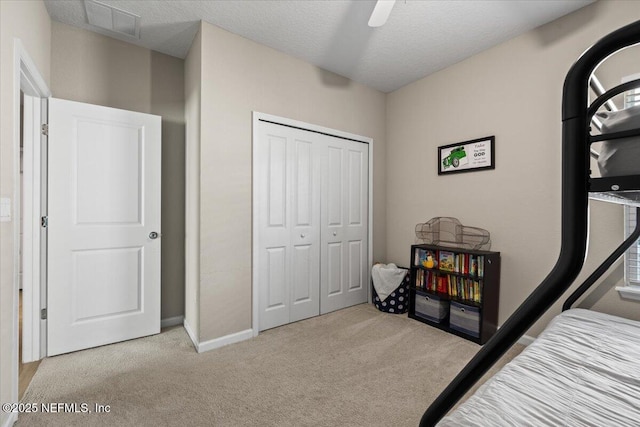 carpeted bedroom featuring a textured ceiling, a closet, and ceiling fan