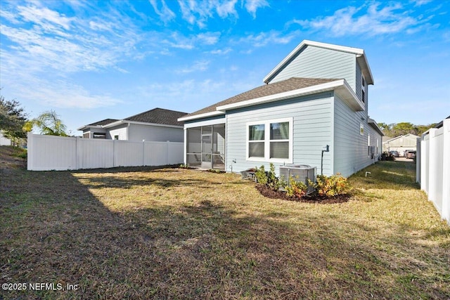 back of property with a sunroom, a lawn, and central AC