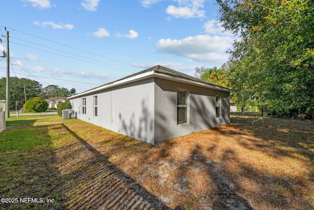 view of side of property featuring central AC unit and a lawn