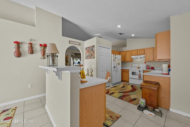 kitchen with vaulted ceiling, kitchen peninsula, white appliances, a kitchen breakfast bar, and light tile patterned floors