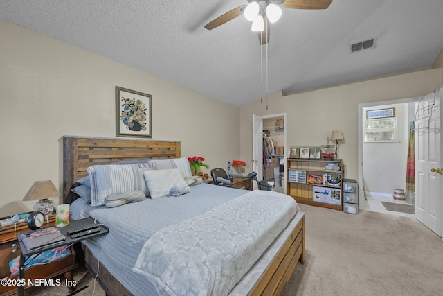 bedroom featuring ceiling fan, a textured ceiling, light carpet, a walk in closet, and a closet