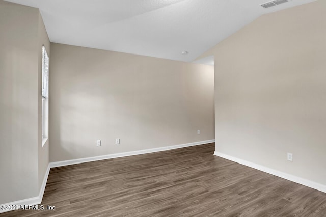 spare room featuring vaulted ceiling and dark wood-type flooring