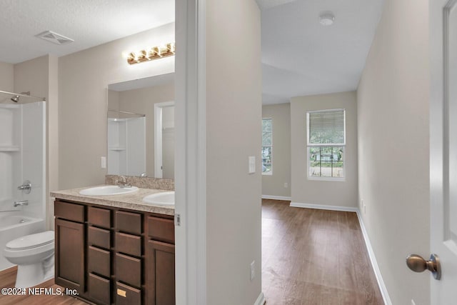 full bathroom with toilet, vanity, shower / bathing tub combination, wood-type flooring, and a textured ceiling