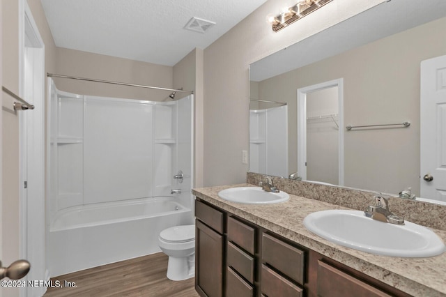 full bathroom with toilet, hardwood / wood-style floors, washtub / shower combination, a textured ceiling, and vanity