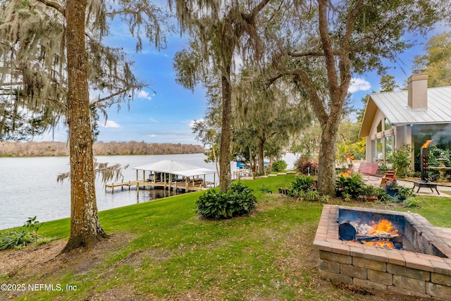 view of yard featuring a water view, a boat dock, and a fire pit