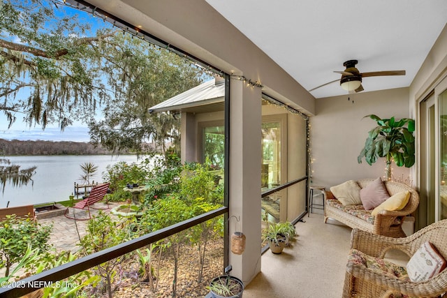 sunroom / solarium with ceiling fan and a water view