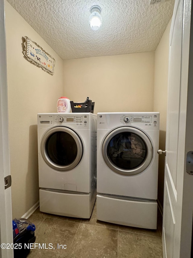 laundry room with separate washer and dryer and a textured ceiling