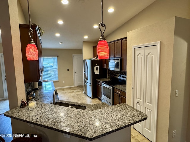 kitchen with vaulted ceiling, sink, light tile patterned floors, kitchen peninsula, and stainless steel appliances