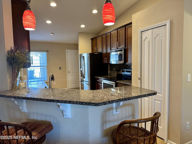 kitchen featuring appliances with stainless steel finishes, kitchen peninsula, and a breakfast bar area