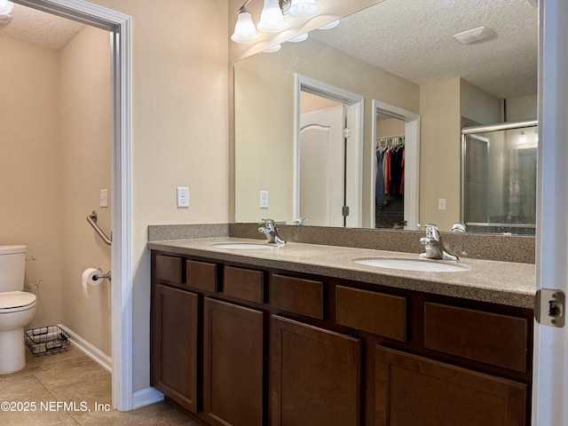 bathroom featuring vanity, a shower with door, toilet, and a textured ceiling