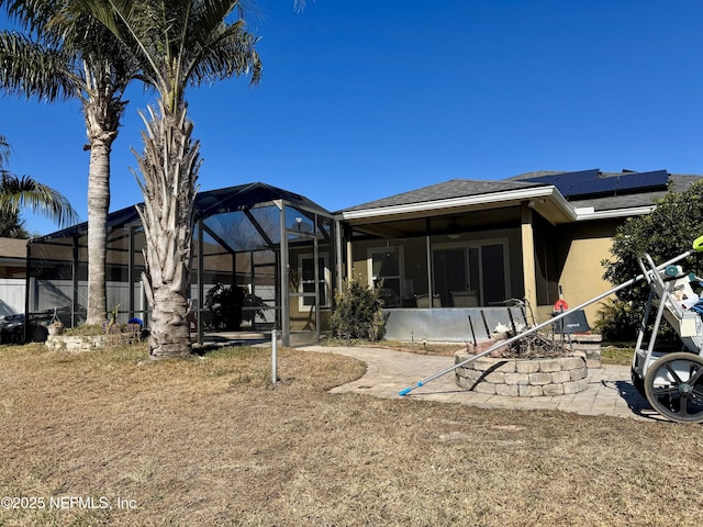 back of property with glass enclosure and solar panels