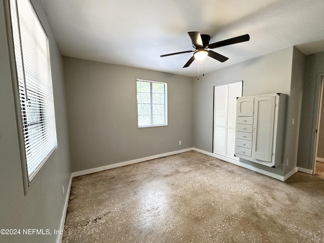 unfurnished bedroom with ceiling fan, a closet, and concrete flooring