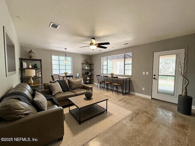 living room with baseboards, finished concrete flooring, visible vents, and plenty of natural light