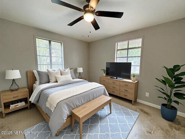 bedroom featuring light carpet, multiple windows, ceiling fan, and baseboards