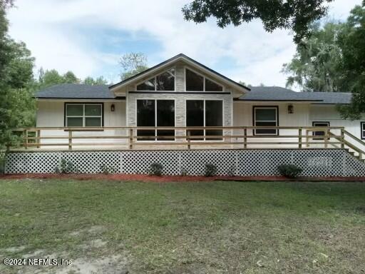 back of house featuring a wooden deck and a yard