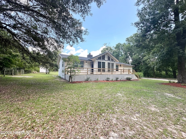 rear view of house with a wooden deck and a yard