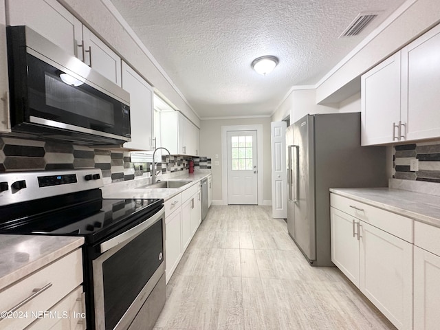 kitchen with appliances with stainless steel finishes, decorative backsplash, white cabinets, and sink