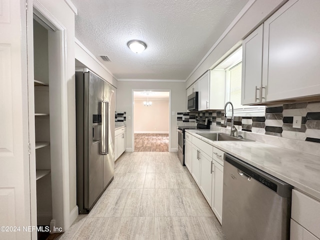 kitchen featuring a textured ceiling, stainless steel appliances, white cabinets, and sink