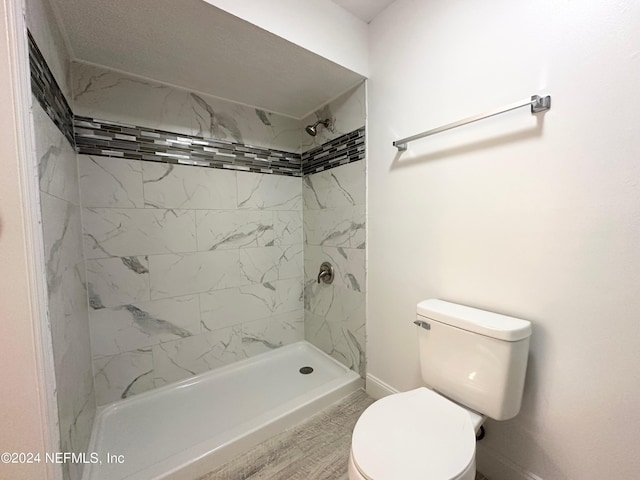 bathroom with tiled shower and toilet