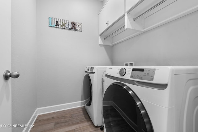 clothes washing area with dark wood-type flooring, cabinets, and washer and clothes dryer