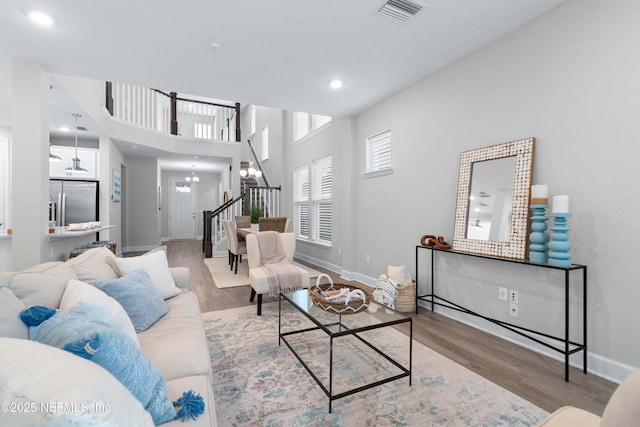 living area featuring wood finished floors, visible vents, stairway, and baseboards