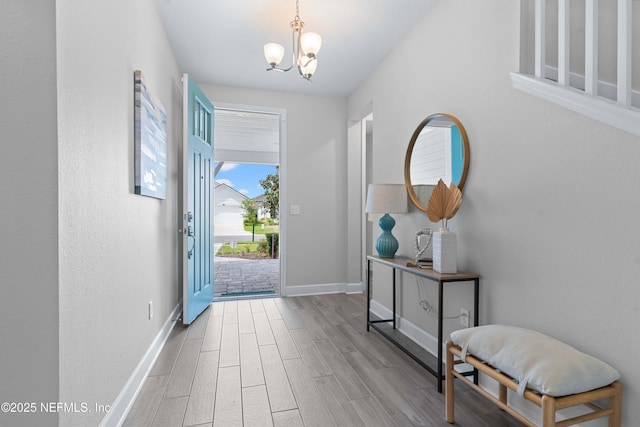 foyer with an inviting chandelier, wood finished floors, and baseboards