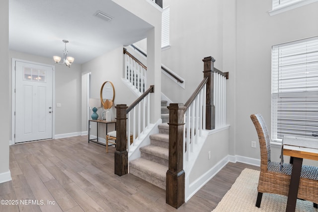 entryway featuring a chandelier, stairway, wood finished floors, and visible vents