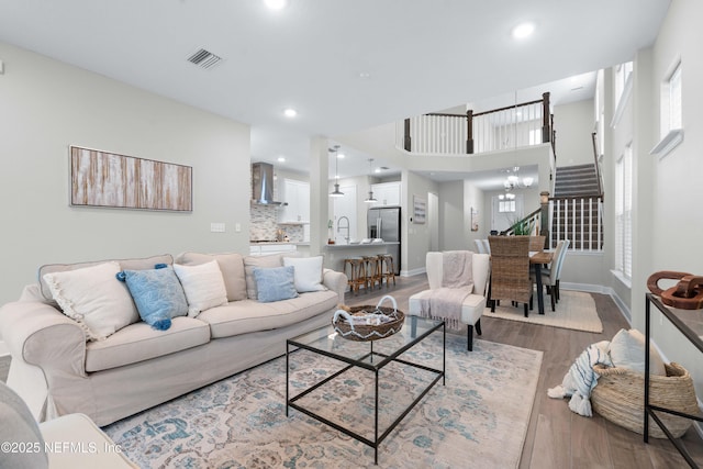 living room featuring visible vents, stairway, wood finished floors, and baseboards