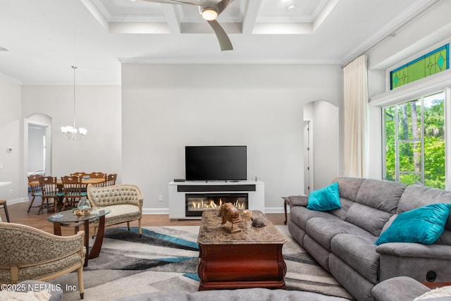 living room featuring arched walkways, coffered ceiling, baseboards, ornamental molding, and light wood-type flooring