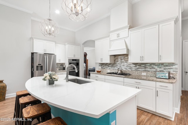 kitchen with stainless steel appliances, an island with sink, custom exhaust hood, and a kitchen breakfast bar