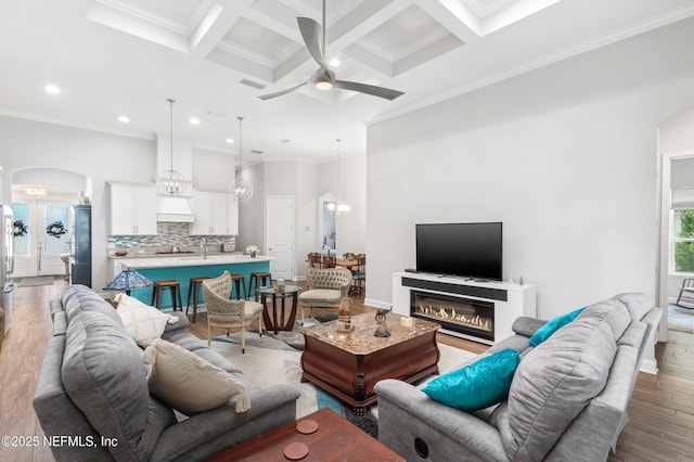 living room with ornamental molding, arched walkways, coffered ceiling, and light wood finished floors